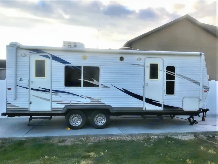 Spacious white travel trailer RV rental, ready for your next trip. Parked on concrete with dual axles.. Forest River Wildwood 2010
