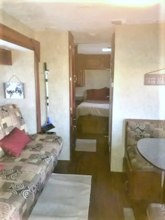 RV rental interior: A practical layout with a patterned sofa, dining booth, and a private bedroom at the back.. Forest River Wildwood 2010