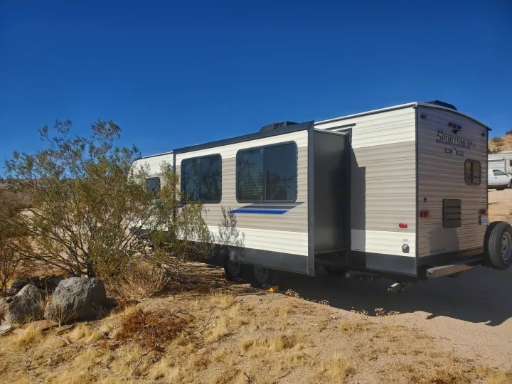 RV rental: a travel trailer with an extended slide-out, set up for desert camping under a clear blue sky.. K-Z Manufacturing Sportsmen 2019