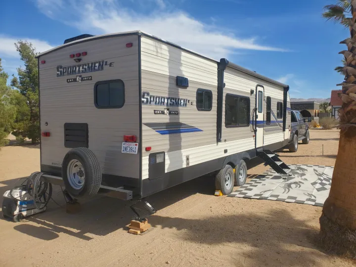 Spacious rv rental travel trailer with generator & leveling jacks at a sunny desert campsite.. K-Z Manufacturing Sportsmen 2019