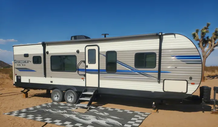 Spacious Sportsmen LE rv rental parked in desert for remote camping, featuring an outdoor mat and Joshua tree.. K-Z Manufacturing Sportsmen 2019