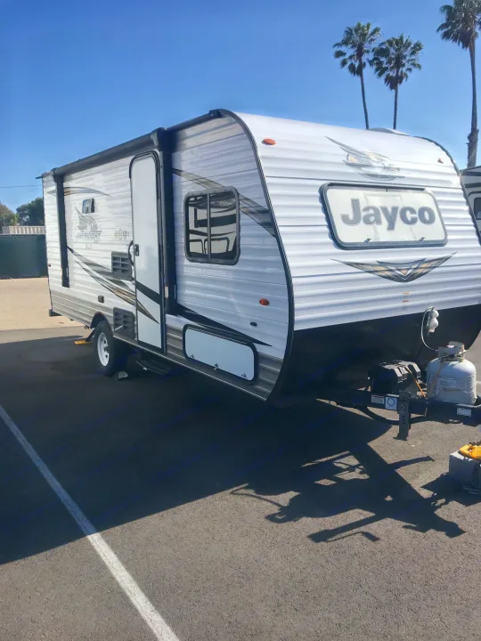Modern Jayco Jay Flight SLX rv rental parked on asphalt under a blue sky. This white travel trailer is ready for adventure.. Jayco Jay Flight 2019