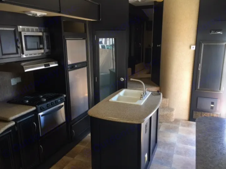 Explore this RV rental's modern kitchen: black cabinets, stainless steel appliances, & island sink. Ideal for travel.. Heartland Torque 2015