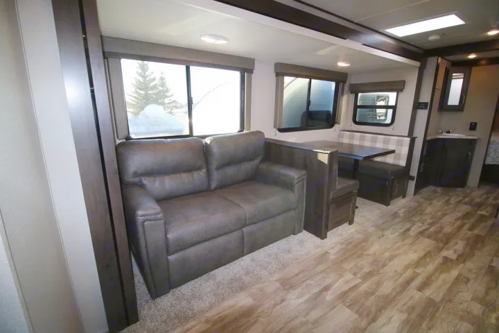 Experience comfort in this RV rental's living area, featuring a sofa, dinette, and bright windows with snowy outdoor views.. Grand Design Other 2021