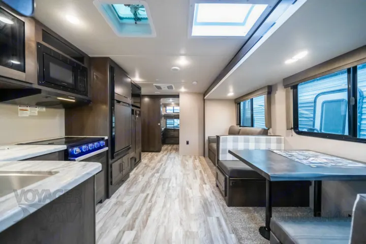 Modern RV rental interior with kitchen, dinette, living area, and light wood-look flooring. Bright and spacious.. Grand Design Other 2021