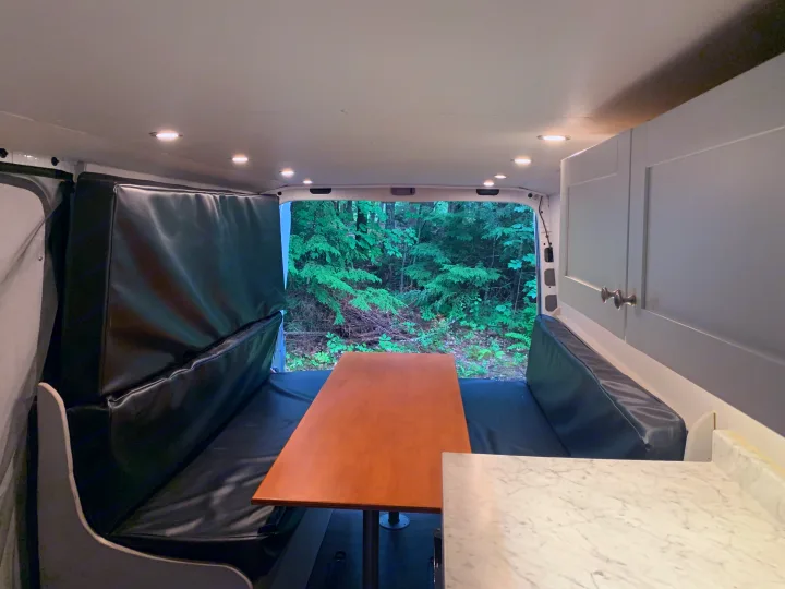 Explore this RV rental's versatile van interior. Features padded benches, dining table, storage, and a forest view.. Mercedes-Benz B class campervan MB 140 2014