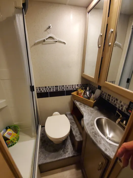 Compact RV rental bathroom with shower (left), toilet (center), and sink (right). Efficient use of space for travel.. Thor Motor Coach Outlaw 2021