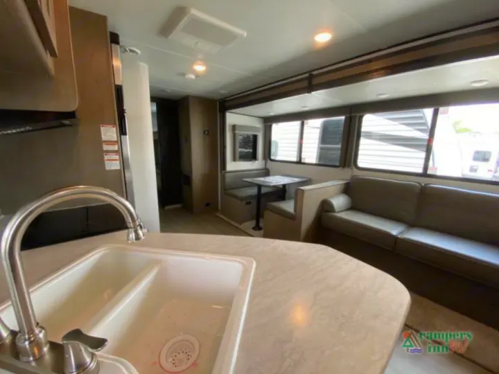 Spacious RV rental interior featuring a kitchen sink, dining booth, and sofa. Bright, modern, and ready for your adventure.. Keystone Hideout 2021