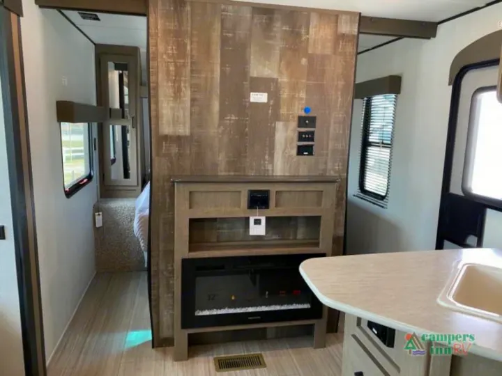 Modern RV rental interior: living space with fireplace, kitchen, and hallway leading to the bedroom.. Keystone Hideout 2021