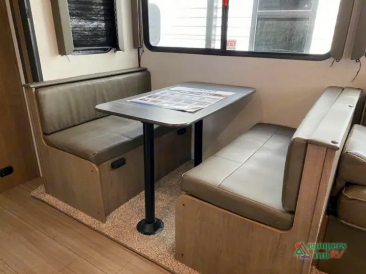 Cozy RV rental dinette: a compact space with comfortable booth seating and a table for dining.. Keystone Hideout 2021