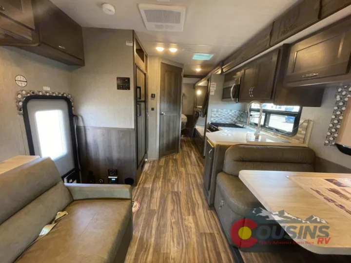 Inside an RV rental: a modern kitchen with sink & stove, sofa seating, and a dining table with patterned upholstery.. Nexus Rebel 2022