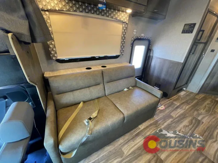 Interior of an RV rental: a modern living area with a taupe sofa, window, and wood-look flooring. Ready for your adventure.. Nexus Rebel 2022