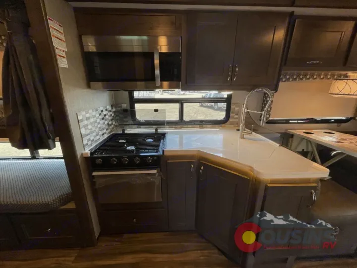 RV rental interior: fully equipped kitchen with stove, microwave, sink, and cozy dining nook for your travels.. Nexus Rebel 2022