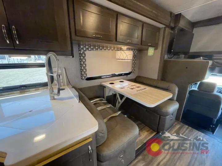 Inside this RV rental: modern kitchen with sink, cozy dinette, and front cab view. Enjoy comfortable motorhome travel!. Nexus Rebel 2022