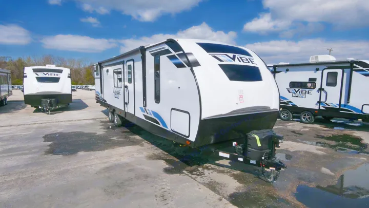 Modern white Vibe travel trailer ready for RV rental, parked on a dealership lot under a blue sky.. Forest River Vibe 2021