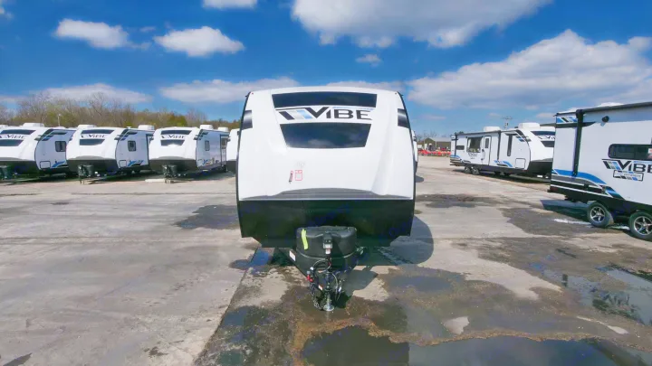 Front view of a new Vibe travel trailer, part of a large RV rental inventory in an outdoor lot under blue skies.. Forest River Vibe 2021