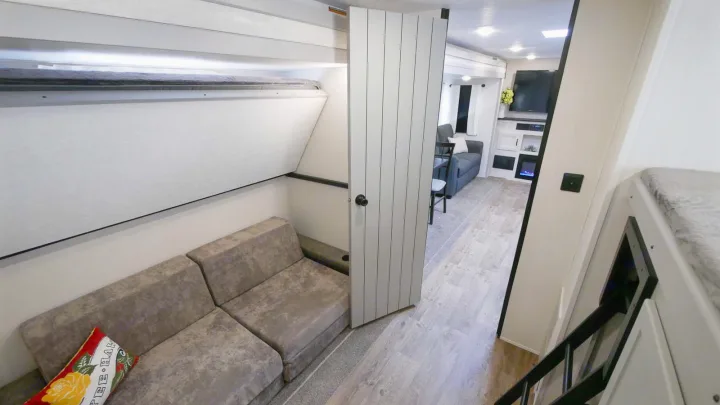 Modern RV rental interior: bunkhouse zone with sofa, and main living area with entertainment, perfect for family comfort.. Forest River Vibe 2021