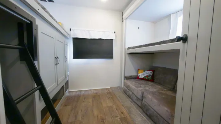 Compact RV rental bunk room with comfy sofa bed, ladder to upper bunk, and wall screen for entertainment.. Forest River Vibe 2021