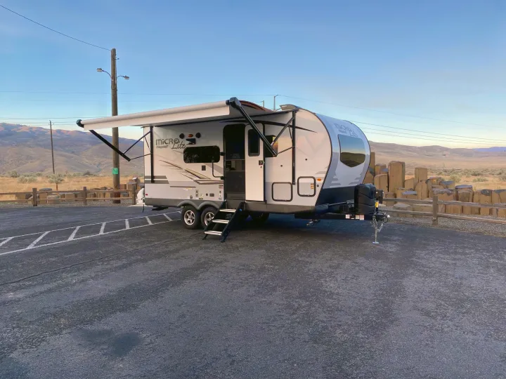 A Flagstaff Micro Lite travel trailer rv rental is set up with its awning extended, parked in a scenic outdoor area.. Flagstaff Micro Lite 2021
