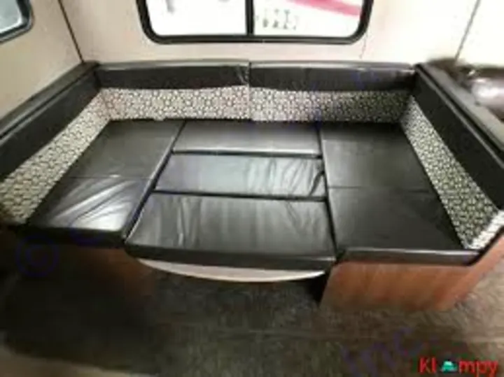 This RV rental features a U-shaped dinette with black cushions, converted into a bed. Perfect for sleeping in your travel trailer.. Heartland Prowler Lynx 2019