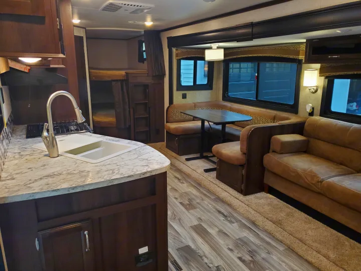This cozy rv rental interior features a kitchen with a sink, comfortable dinette, sofa, and spacious bunk beds.. Jayco Jay Flight 2018