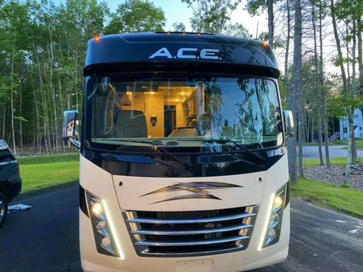 Experience an RV rental! Front view of a Class A motorhome parked outdoors with lights on, ready for adventure.. Thor Motor Coach A.C.E 2021