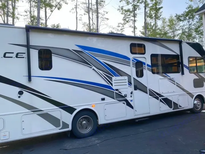 A sleek white RV with striking blue, black, and gray graphics, ideal for an RV rental outdoor escape.. Thor Motor Coach A.C.E 2021