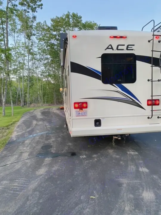 Rear view of an A.C.E. motorhome, an RV rental, parked on asphalt with red lights on.. Thor Motor Coach A.C.E 2021