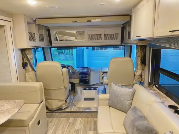 Explore this inviting RV rental interior: a modern cabin with driver's seat, dining booth, and sofa seating.. Thor Motor Coach A.C.E 2021