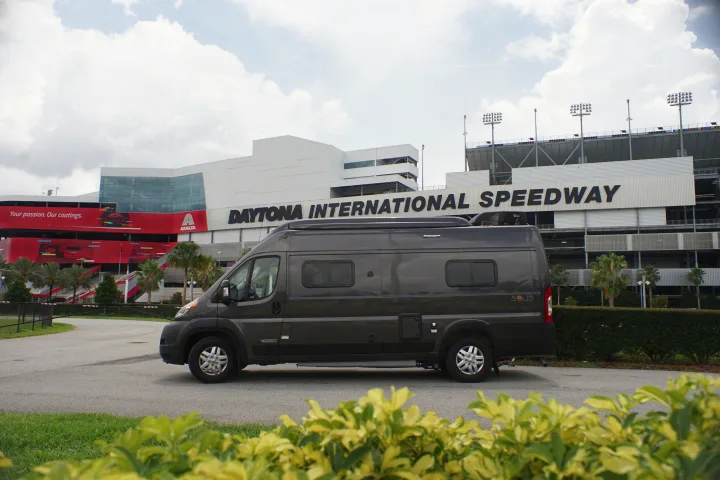 RV rental: A dark grey Winnebago Solis camper van parked at Daytona International Speedway. Ready for your next adventure!. Winnebago Other 2022