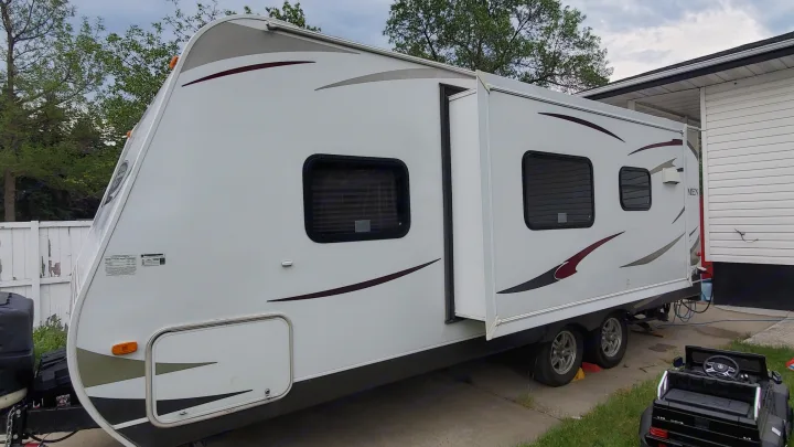 Spacious white travel trailer, ideal for an RV rental, parked with slide-out expanded at a residence.. Dutchmen Dutchmen 2012
