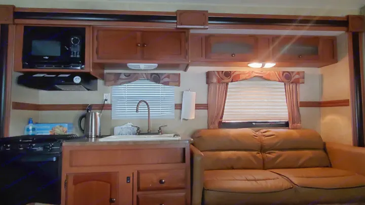 Spacious RV rental interior features a kitchen with microwave, stovetop, and sink, plus a comfortable sofa in the living area.. Dutchmen Dutchmen 2012