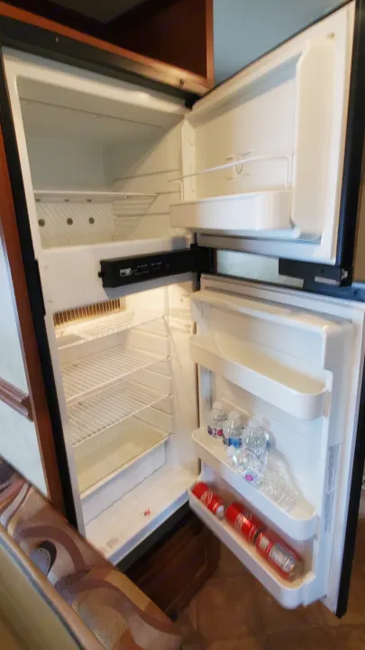 Interior of an open RV rental refrigerator, featuring a clean freezer and cold drinks, ready for your adventure!. Dutchmen Dutchmen 2012