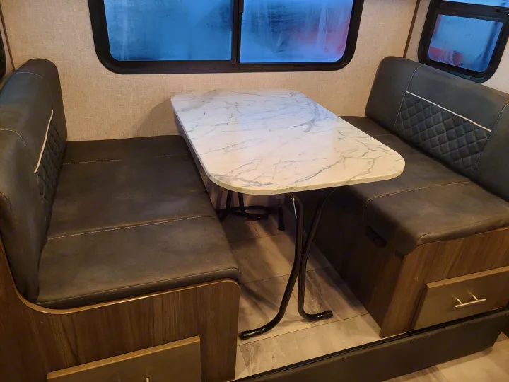 RV rental interior showing a comfortable dinette with dark gray upholstered benches and a marble-patterned table.. Dutchmen Kodiak 2021