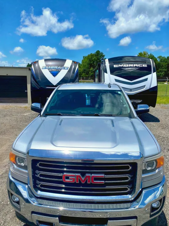 Silver GMC truck with two "Embrace Ultra-Lite" RVs in a gravel lot, ready for your next RV rental adventure!. Other Other 2018