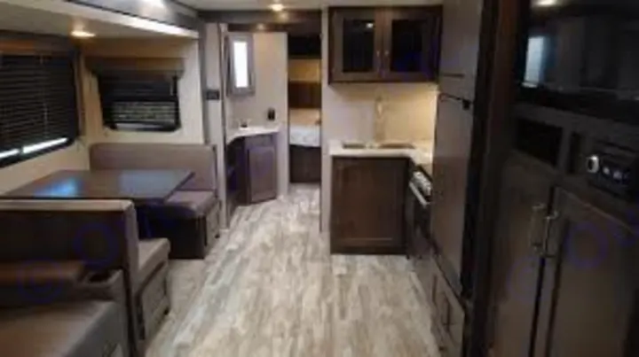 This RV rental interior showcases a modern living space with a dining booth, full kitchen, and a bedroom visible beyond.. Grand Design Other 2021