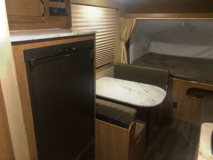 This RV rental's interior features a compact kitchen with Dometic fridge, a cozy dinette, and a spacious pop-out bed.. Starcraft Launch 2018