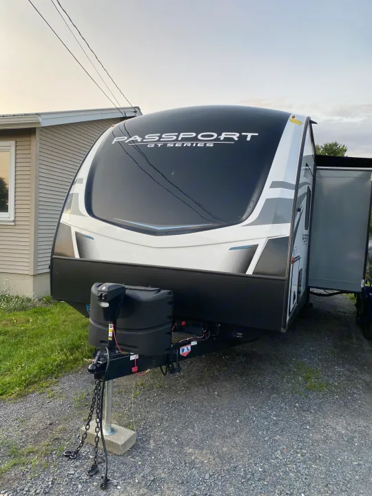 Black and white Passport GT Series travel trailer, a great option for an RV rental or camping trip. Parked on a gravel driveway.. Keystone Passport 2021