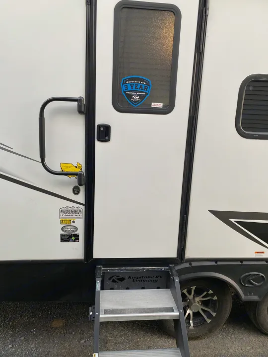 View of a white Keystone Passport travel trailer with steps & door, perfect for your next rv rental camping adventure.. Keystone Passport 2021
