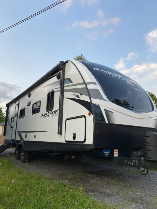 A white Keystone Passport travel trailer, an excellent choice for an RV rental adventure.. Keystone Passport 2021