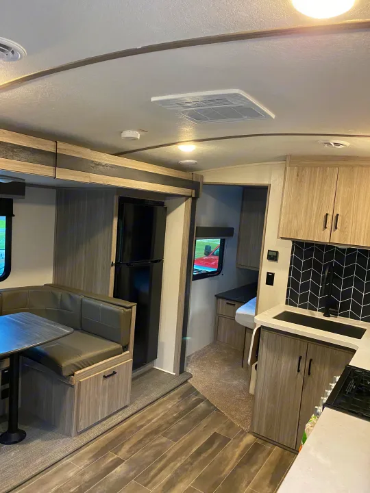 Spacious RV rental interior with dinette, kitchen, and modern decor, offering a comfortable travel experience.. Keystone Passport 2021