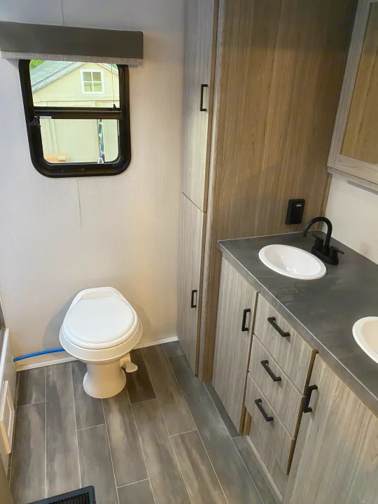 Modern RV rental bathroom with dual sinks, toilet, and sleek cabinetry for comfortable travel.. Keystone Passport 2021
