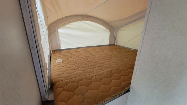 RV rental's cozy pop-out bed, featuring a brown quilted mattress, offers a comfortable sleeping space.. Forest River 16RB 2019