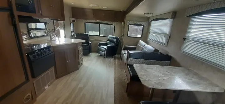 Spacious rv rental interior featuring kitchen, living area with recliners and sofa, and dining booth with table. Modern, functional design.. geo 267RL 2018
