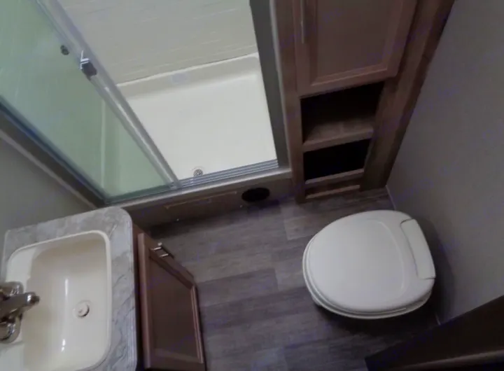 RV rental bathroom features a compact sink, toilet, and shower with a sliding door, maximizing space for travel.. Coachmen Catalina 2021