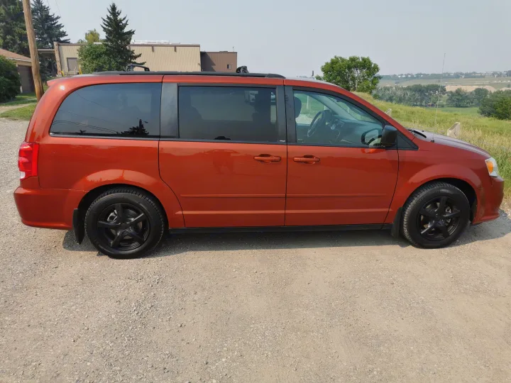 Vibrant orange minivan on gravel. Great for travel! Explore our reliable vehicles or consider an RV rental.. Dodge Other 2012
