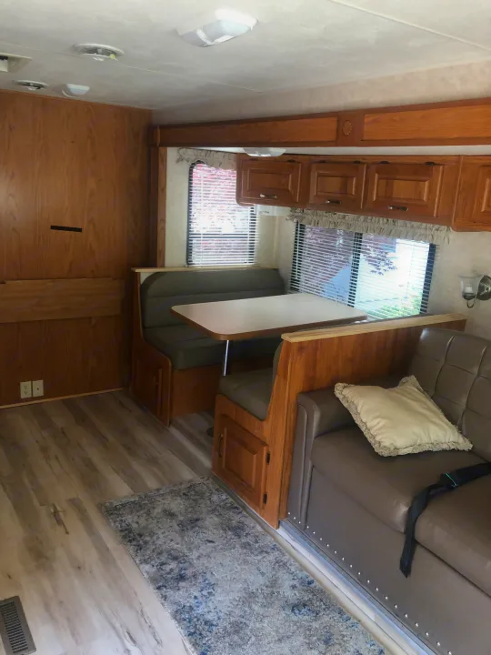 RV rental interior featuring a dinette with grey seating, a sofa, and wood cabinets. Ideal for travel.. Damon Daybreak 2005
