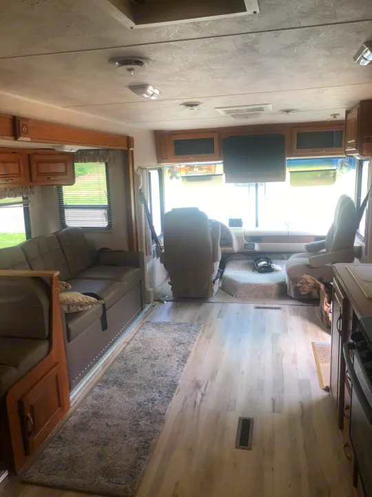 Inside a well-appointed RV rental, featuring a lounge, cockpit, and kitchen area with light wood-look flooring.. Damon Daybreak 2005