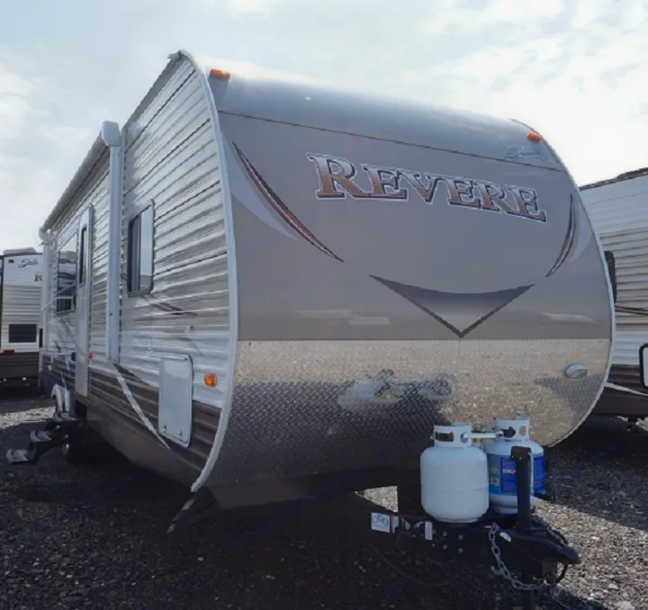 Revere travel trailer RV rental. Light brown camper with a diamond plate front and propane tanks, parked outdoors.. Shasta Oasis 32 DS 2020