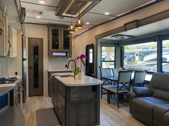 Modern rv rental interior with kitchen island, dining table, and recliner seating. Bright and spacious for your adventures.. Alliance RV Paradigm 2021